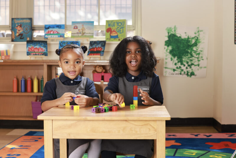 Two young students sitting at a desk with building blocks